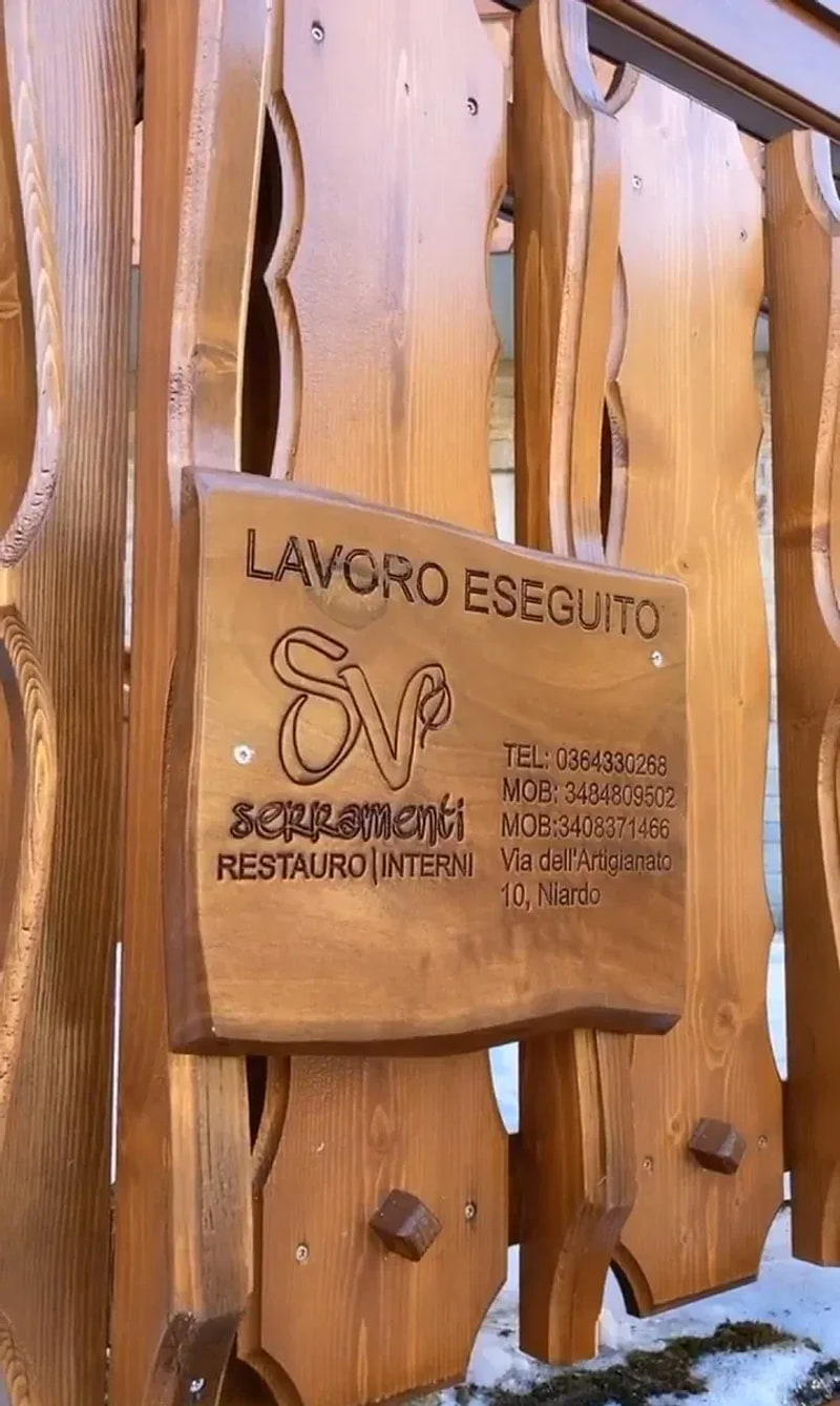 Targa in legno intagliata «LAVORO ESEGUITO» con il marchio SV Serramenti, fissata a un parapetto