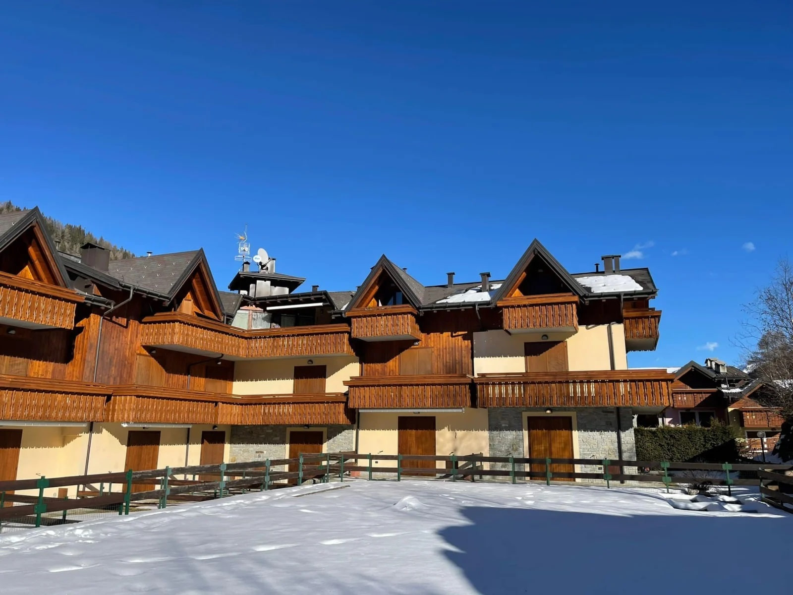 Complesso di case in legno con balconi restaurati, in una giornata di neve