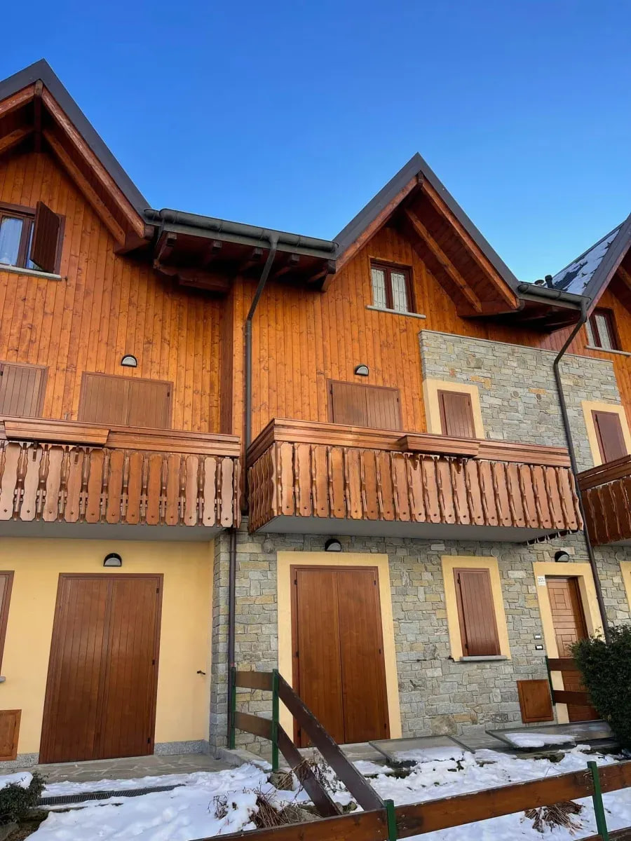 Facciata in legno e pietra con balconi e portoncini restaurati