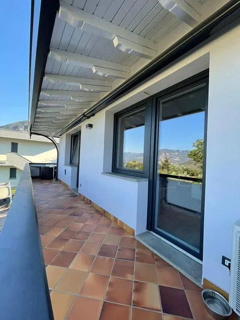 Terrazzo con serramenti in alluminio scuro e tettoia in legno chiaro