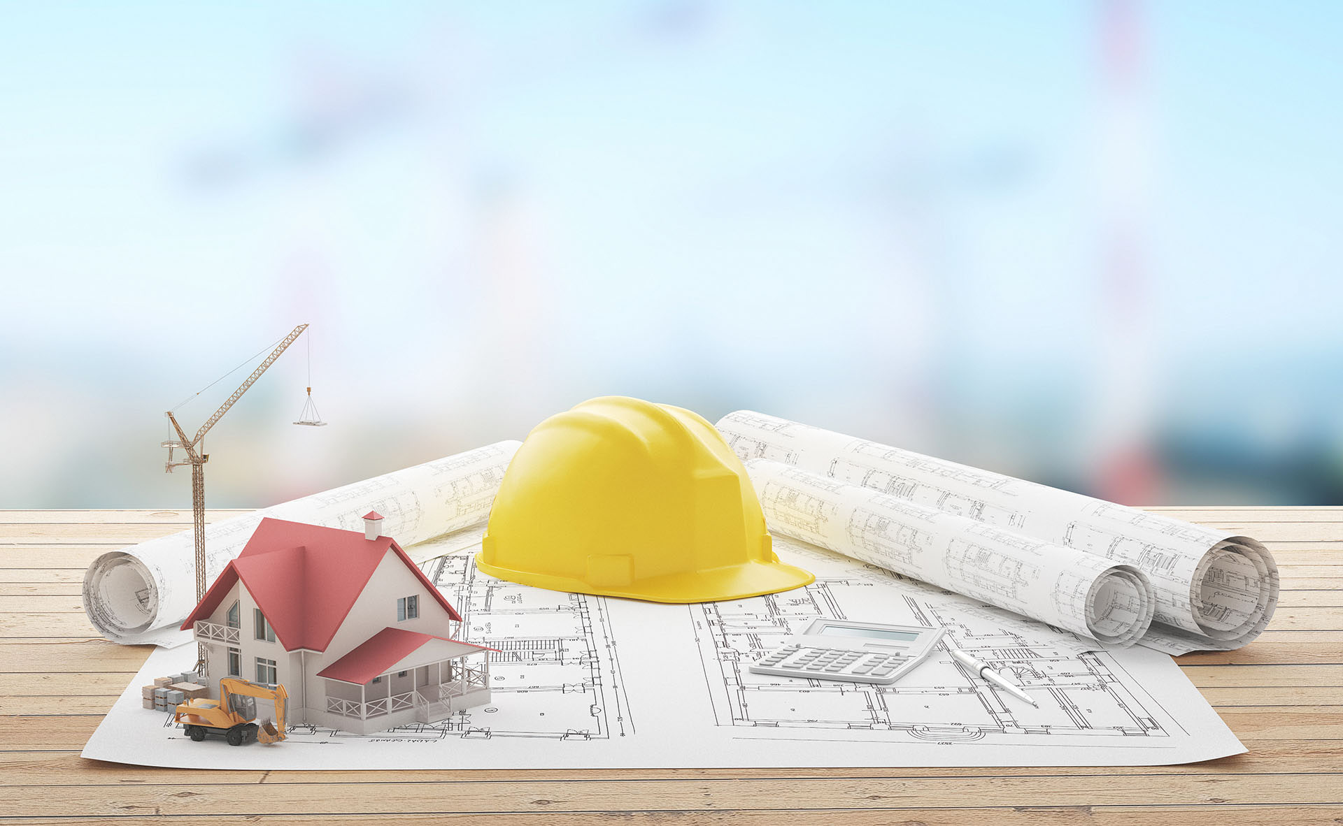 Elmetto da cantiere e disegni tecnici su un piano di legno